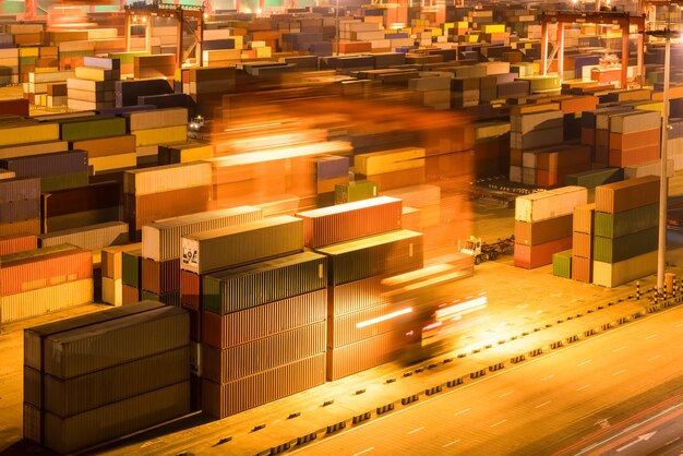 Shipping container stack yard at night light trails of industrial crane motion blur