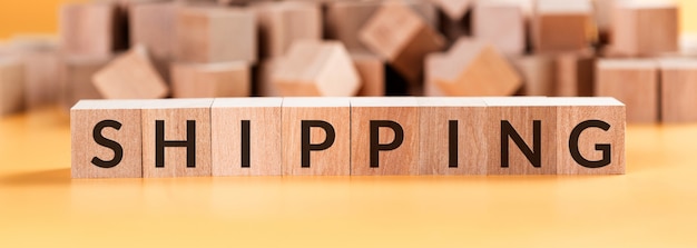 Shipping Word Written In Wooden Cube. Blurred Wooden Cube background.