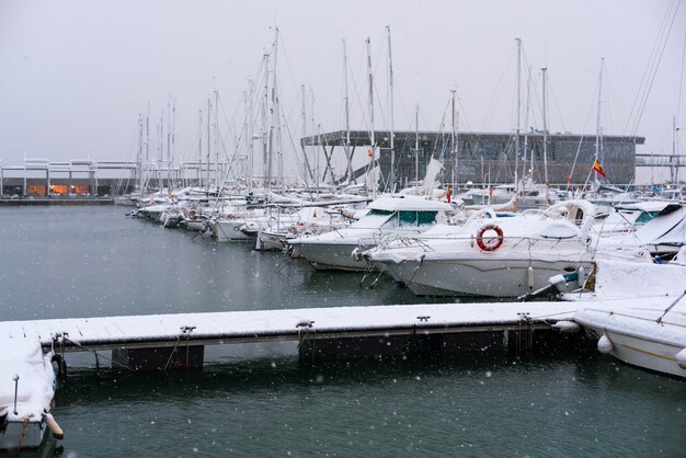 スペインの町デニアの港で雪で覆われた船やボート