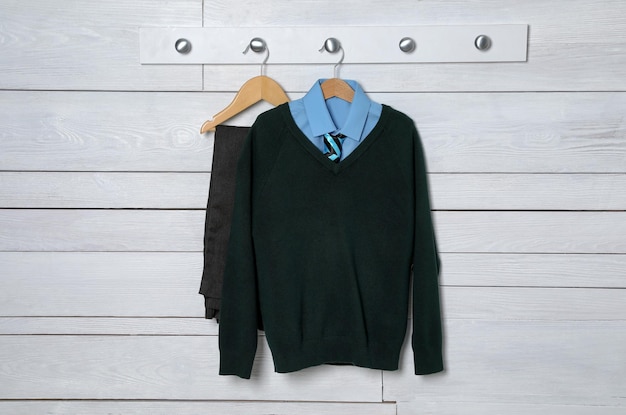 Shirt jumper and pants hanging on white wooden wall School uniform