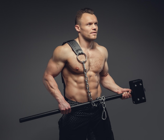 Shirtless athletic man holds big cross fit hummer.