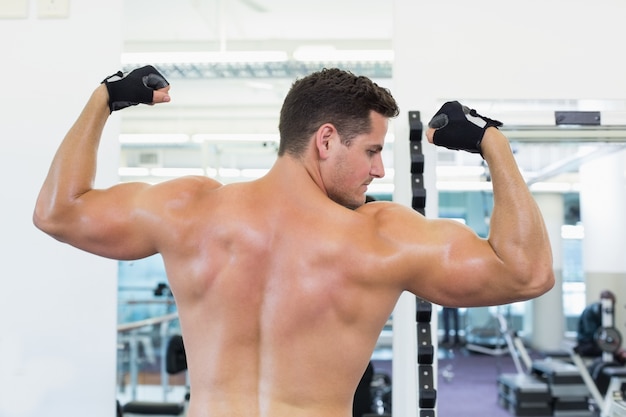 Shirtless bodybuilder buigt zijn biceps