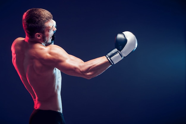 Shirtless boxer with gloves on dark background. Isolate