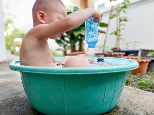 Photo shirtless boy sitting in container outdoors