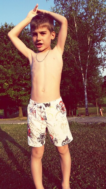 Photo shirtless boy standing at park