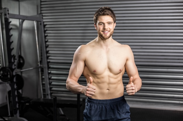 Shirtless fit man thumbs upat gym