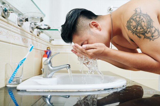 Shirtless fit man washing face
