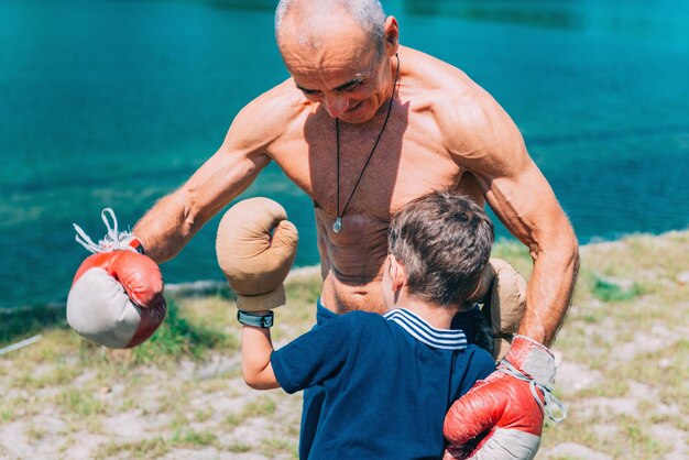 Shirtless grandfather with grandson boxing by swimming pool