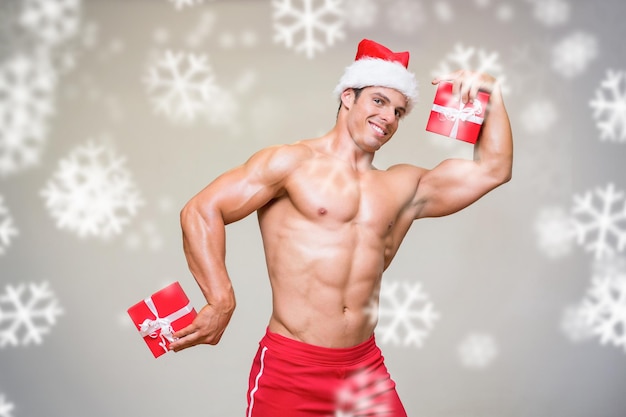 눈송이에 대 한 선물을 들고 산타 모자에 shirtless 사나이 남자