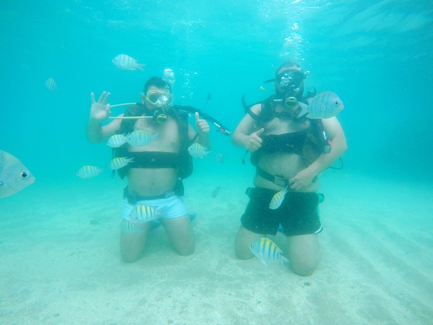 Shirtless male friends scuba diving undersea