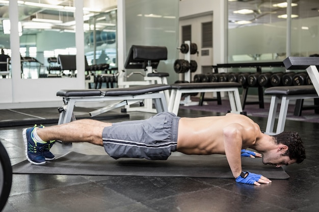 Shirtless man doen push-up in de sportschool