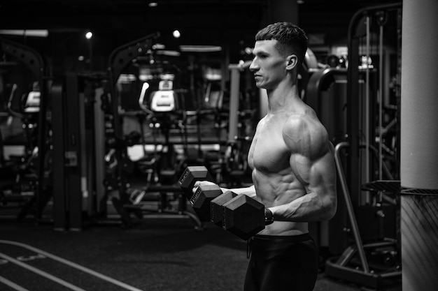 Shirtless man doing bicep tricep curls with dumbbells in gym strength workout