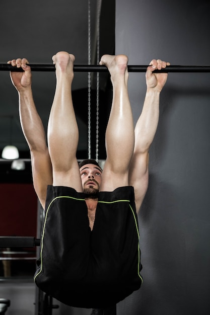 上半身裸の男がcrossfitジムでプルアップを行う