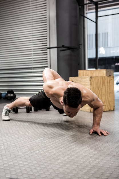 Человек без рубашки делает push up в тренажерном зале crossfit