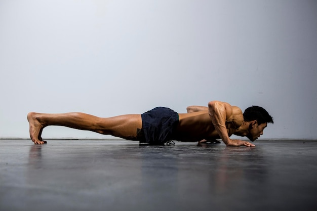 Photo shirtless man doing push-ups against wall