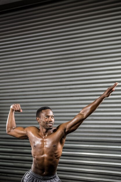 Shirtless man flexing muscles at the crossfit gym