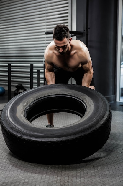 Crossfit 체육관에서 무거운 타이어를 내리고 벗은 남자