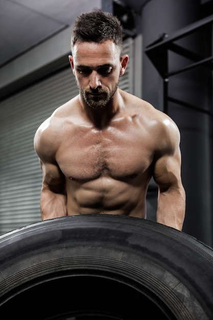 Crossfit 체육관에서 무거운 타이어를 내리고 벗은 남자