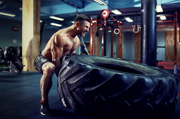 Shirtless man flipping heavy tire