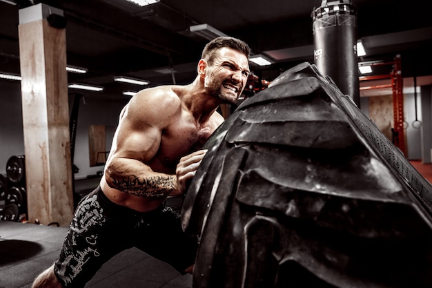 Shirtless man flipping heavy tire