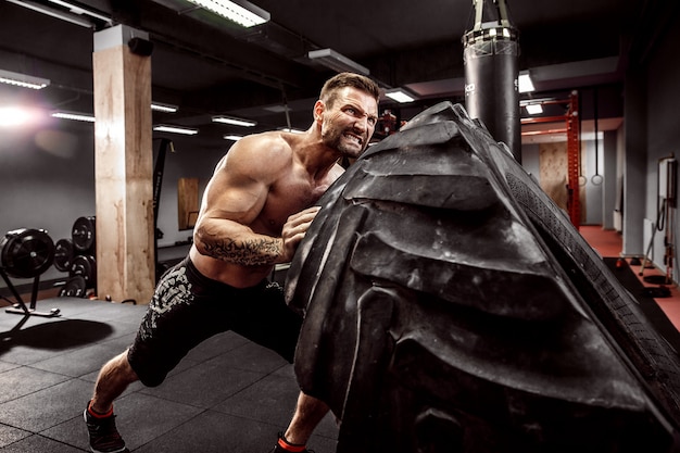 Shirtless man flipping heavy tire