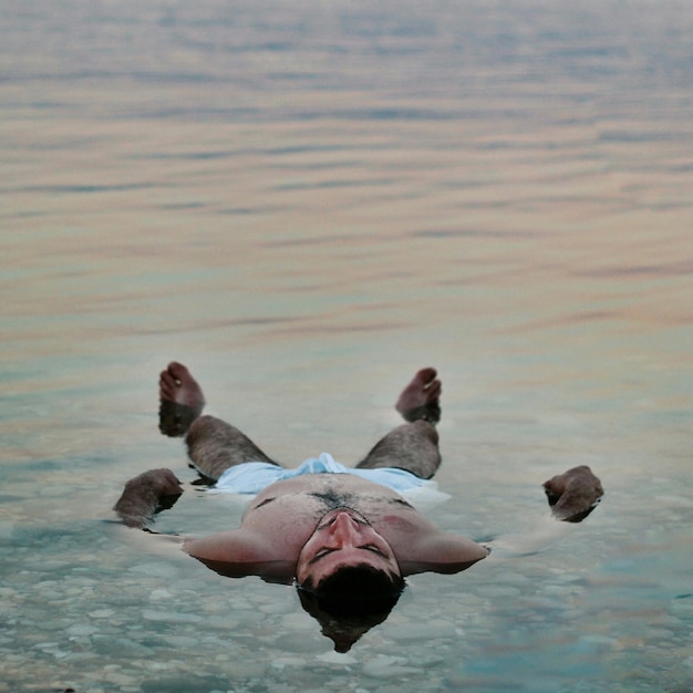 Foto uomo senza camicia che galleggia sul lago