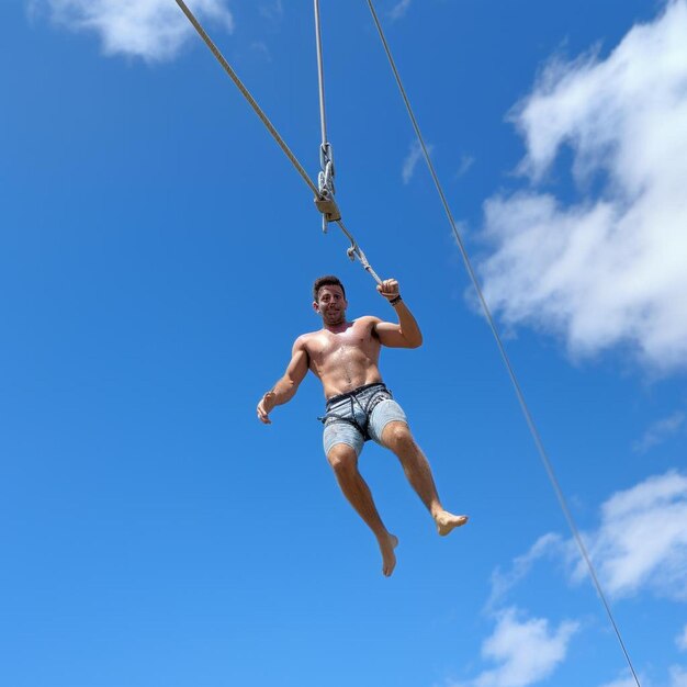 A shirtless man is suspended on a rope