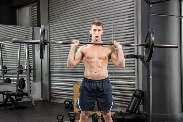 Shirtless man lifting barbell at the crossfit gym