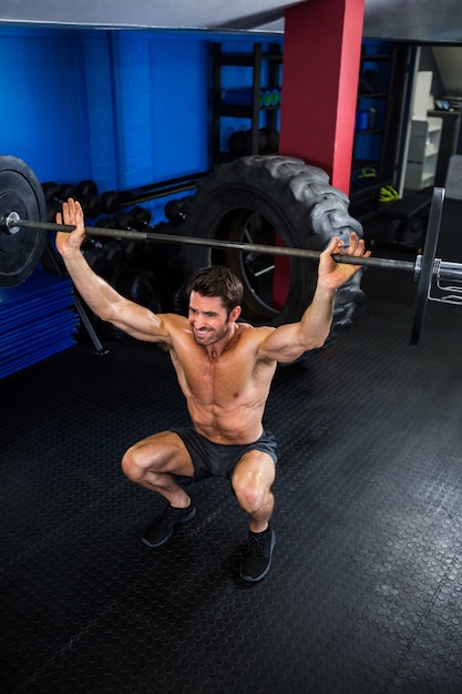 Shirtless man lifting barbell in gym