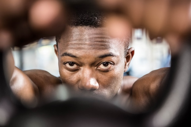 Shirtless man lifting heavy kettlebell at the crossfit gym