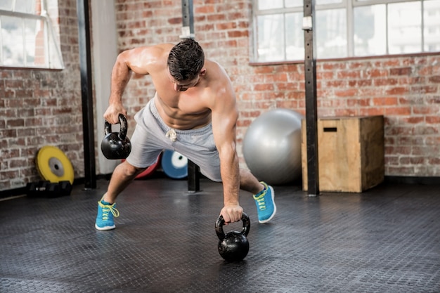 Shirtless man lifting kettlebell