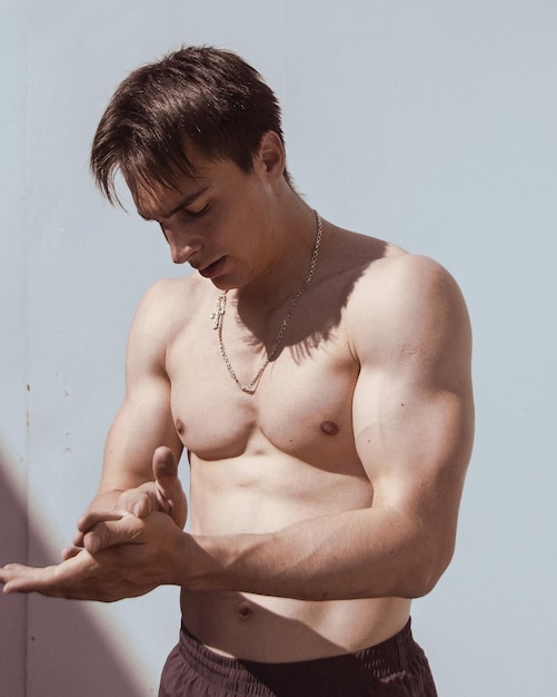 Shirtless man looking away against white wall