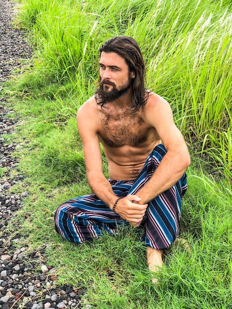 Photo shirtless man looking away while sitting on field