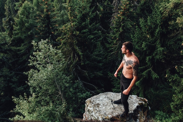 Shirtless man on rock looking away