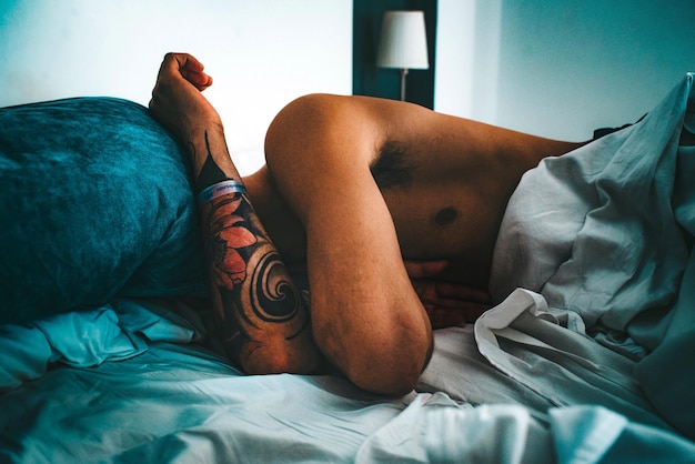 Photo shirtless man sleeping on bed at home