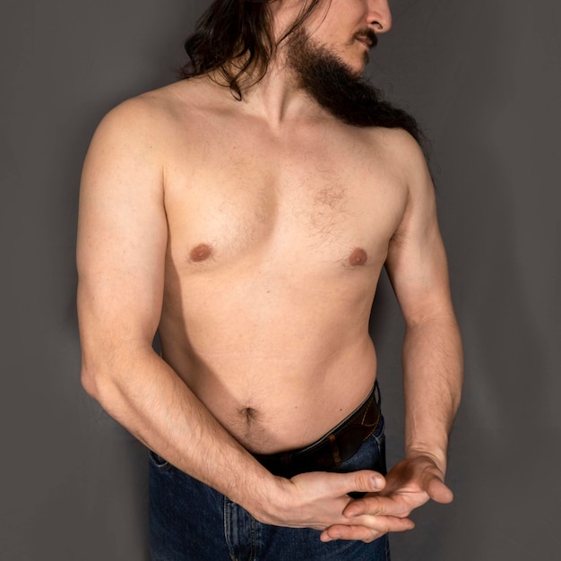 Shirtless man standing against black background
