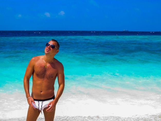 Shirtless man standing at beach against sky