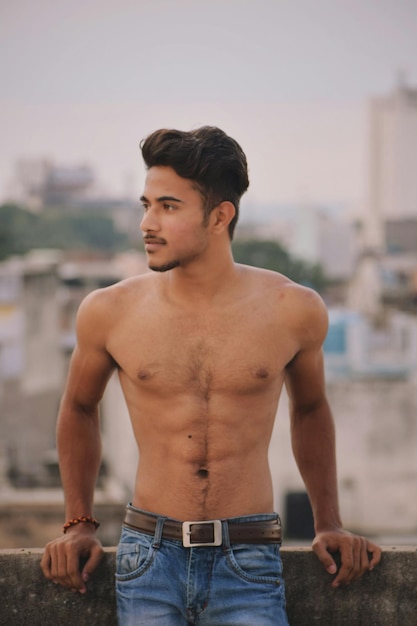 Shirtless man standing by retaining wall