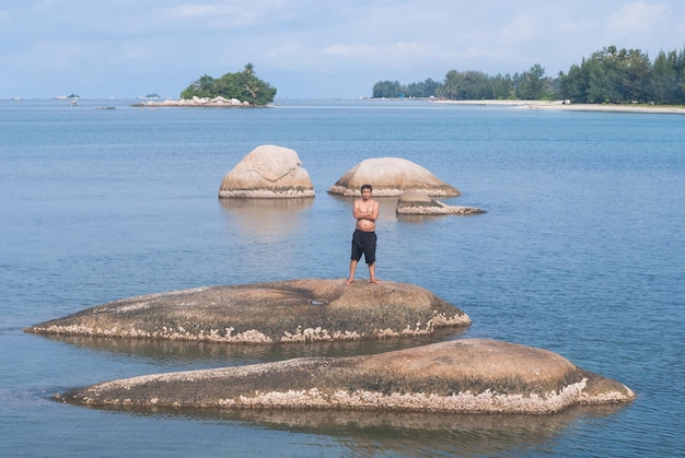 Foto uomo senza camicia in piedi su una roccia in mezzo al fiume