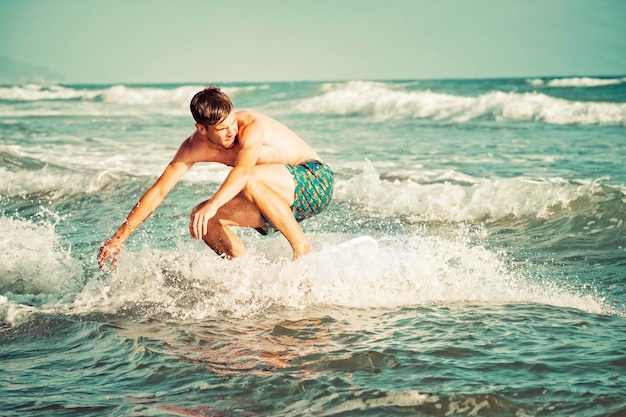 写真 シャツのない男が海でサーフィンをしている