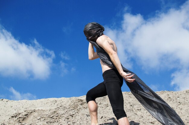 写真 シャツのないスカーフをかぶった男が空に立っています ⁇