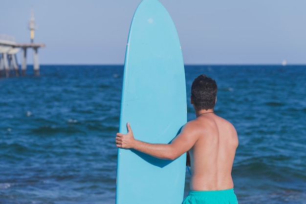 shirtless man with surfboard at beach