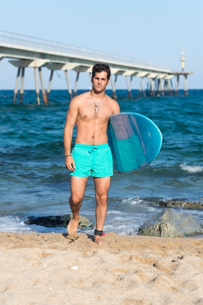 Shirtless man with surfboard at beach