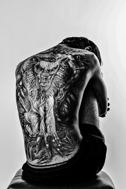 shirtless man with tattoo sitting against wall