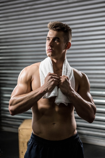 Shirtless man with towel around neck at the gym