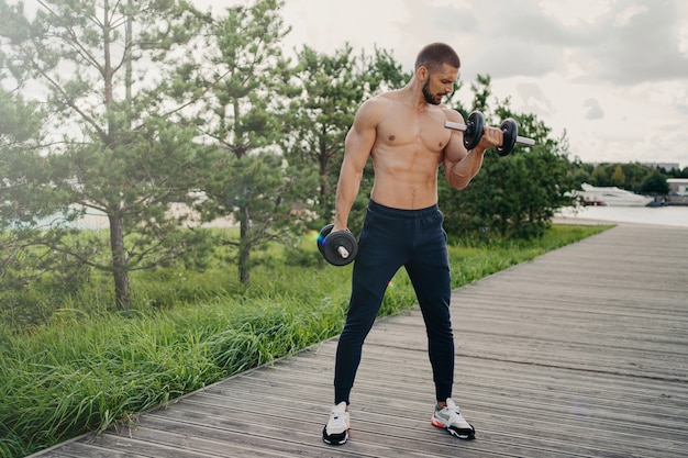 Shirtless man working out outdoors with weights