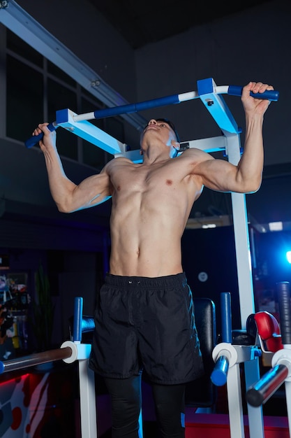 Shirtless mannelijke lichaamsbouwer die trekkracht UPS doen bij de gymnastiek