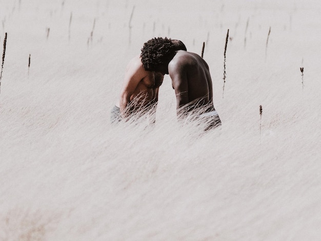 Shirtless men standing amidst plants on field