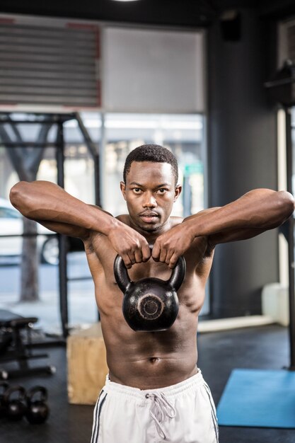 Shirtless mens die zware kettlebell opheffen bij de crossfitgymnastiek