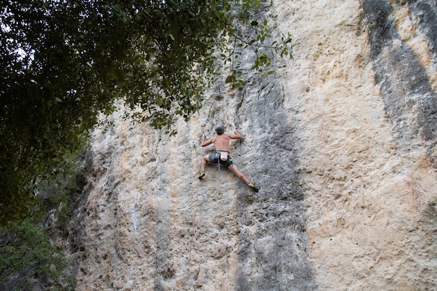 Shirtless mountaineer climbing on rock